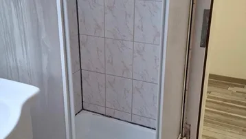 Duschkabine mit weißen Fliesen und einem Waschbecken in einem Badezimmer.