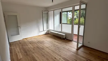 Geräumiges Wohnzimmer mit Holzboden und weitem Blick auf die Umgebung durch große Fenster.