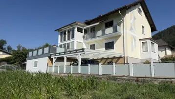 Modernes Haus mit mehreren Balkonen, Carport und Bergblick in sonniger Lage.