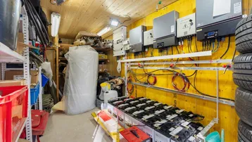 Technikraum mit Solaranlagen-Wechselrichtern, Batterien und Reifenlagerung.