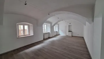 Geräumiger Innenraum mit Gewölbedecke, Holzboden und mehreren Fenstern, ideal für gewerbliche Nutzung.
