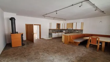 Geräumiger offener Wohnbereich mit integrierter Küche, Essbereich und einem gemütlichen Holzofen.