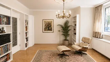 Helles Wohnzimmer mit Parkettboden, elegantem Kronleuchter und integrierten Bücherregalen.