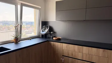 Moderne Küche mit dunklen Arbeitsplatten, Holzfronten und Fensterblick auf die Umgebung.