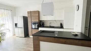 Moderne offene Küche mit Kochinsel, integrierten Geräten und Holzdetails.