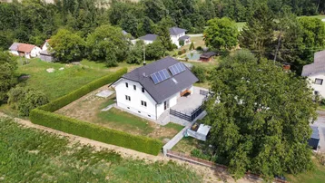 Luftaufnahme eines modernen Einfamilienhauses mit Solaranlage auf dem Dach und gepflegtem Garten.
