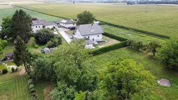 Panoramablick auf das Wohnhaus, umgeben von Feldern und weiteren Häusern in ländlicher Umgebung.