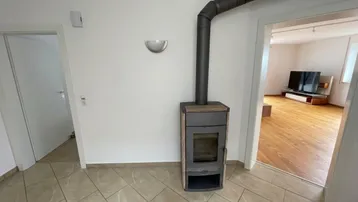 Heller Flur mit modernem Holzofen und Zugang zu weiteren Räumen.