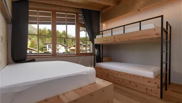 Kinderzimmer mit Etagenbett, Einzelbett und großen Fenstern mit Blick auf die Umgebung.