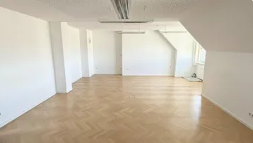 Geräumiger Büroraum mit Fischgrätparkett und abgehängter Decke, bereit zur individuellen Gestaltung.