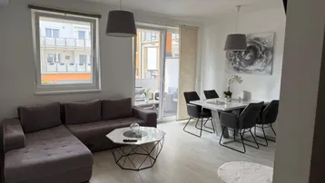 Heller Wohn- und Essbereich mit modernem Sofa, Esstisch und Zugang zum Balkon.