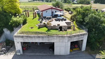 Luftaufnahme des Anwesens mit begrüntem Dach, großer Terrasse und integrierter Garage.