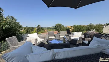 Gemütliche Outdoor-Lounge auf der Terrasse mit weitem Blick über die grüne Landschaft.