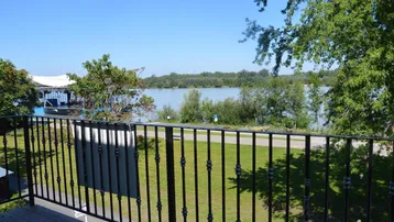 Balkon mit Holzboden und schwarzem Geländer bietet einen weiten Blick auf den Fluss.