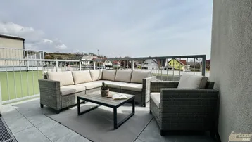 Geräumige Dachterrasse mit bequemen Loungemöbeln, Fliesenboden und Blick auf die Umgebung.