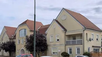 Mehrere gut gepflegte Wohnhäuser mit heller Fassade, Ziegeldächern und Außenparkplätzen.