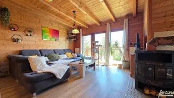 Gemütliches Wohnzimmer mit großem Sofa, Kaminofen und Zugang zum Balkon.