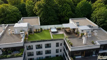 Großzügige Dachterrasse mit Whirlpool, Essbereich und begrünten Flächen, umgeben von Bäumen.