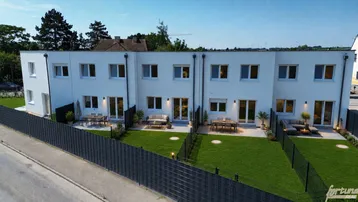 Luftaufnahme von modernen Reihenhäusern mit privaten Gärten und Terrassen bei Tageslicht.