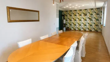Geräumiges Esszimmer mit großem Holztisch, moderner Beleuchtung und dekorativer Tapetenwand.