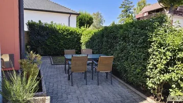 Gemütliche gepflasterte Terrasse mit Gartenmöbeln, umgeben von hohen Hecken für Privatsphäre.
