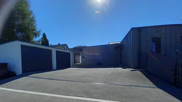 Modernes Haus mit dunkler Fassade und Doppelgarage unter blauem Himmel.