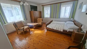 Geräumiges Schlafzimmer mit Holzboden, Doppelbett und gemütlicher Sitzecke am Fenster.