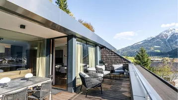Große Dachterrasse mit modernen Outdoor-Möbeln, Esstisch und atemberaubendem Bergblick, ideal zum Entspannen.