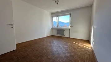Heller Raum mit Parkettboden, weißen Wänden und Blick auf die umliegenden Berge.
