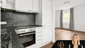 Moderne Küche mit weißen Schränken, dunkler Arbeitsplatte und Blick in den Wohnbereich.