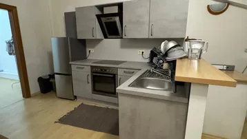 Moderne Küche mit grauen Schränken, Holzbalken und Dachschräge in einem hellen Raum.