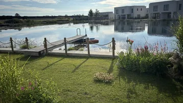 Gepflegter Garten mit direktem Zugang zu einem See und Blick auf moderne Häuser.