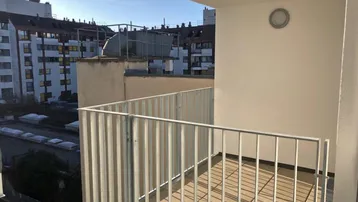 Heller Balkon mit Metallgeländer und Blick auf umliegende Gebäude in der Stadt.
