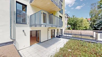 Blick auf die moderne Gebäudefassade mit Balkonen und einer großzügigen, gefliesten Terrasse im Erdgeschoss.