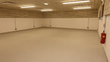 Geräumiger Lagerraum mit hellem Boden, Ziegelwänden und effizienter Deckenbeleuchtung.