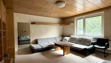 Gemütliches Wohnzimmer mit Sofa, Couchtisch und Blick in einen angrenzenden Raum.