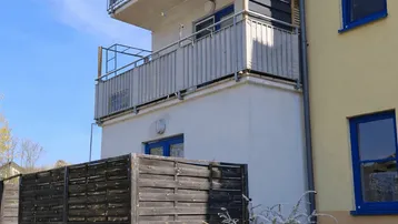 Ansicht der Gebäudefassade mit mehreren Balkonen und einem kleinen Vorgartenbereich.