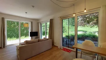 Helles Wohn- und Esszimmer mit Holzboden und großen Schiebetüren zum Gartenbereich.