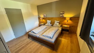 Gemütliches Schlafzimmer mit zwei Einzelbetten, Holzboden und dezenter Wandgestaltung in warmen Tönen.