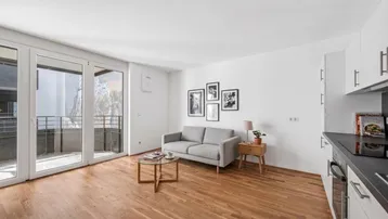 Helles Wohnzimmer mit Holzboden, Zugang zum Balkon und moderner Einrichtung.