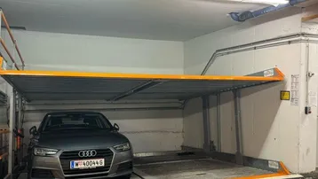 Helle Tiefgarage mit modernem Doppelparker-System und einem geparkten Audi.