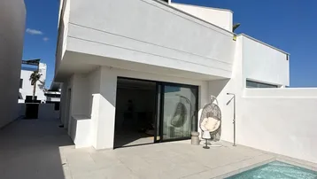 Moderne weiße Villa mit privatem Pool und gefliester Terrasse unter blauem Himmel.