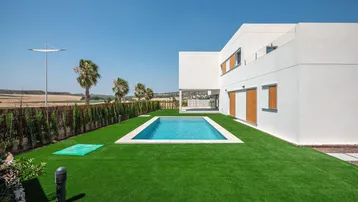 Moderner Neubau mit privatem Pool und gepflegtem Rasen in ländlicher Umgebung.