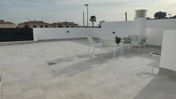 Geräumige Dachterrasse mit Fliesenboden und Gartenmöbeln, ideal für Entspannung im Freien.
