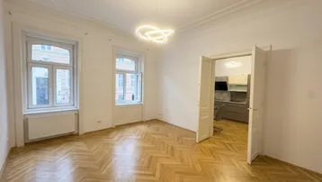 Helles Zimmer mit Fischgrätparkett, hohen Decken und Stuckverzierungen, bereit zur individuellen Gestaltung.