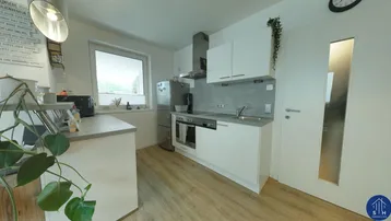 Moderne Küche mit weißen Schränken, Edelstahlgeräten und Fenster, ausgestattet für den täglichen Gebrauch.
