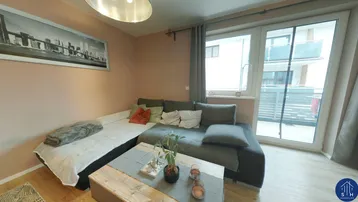 Gemütliches Wohnzimmer mit Ecksofa, Holztisch und Zugang zum Balkon, hell und modern eingerichtet.