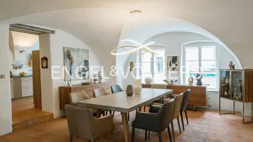 Gewölbter Essbereich mit modernem Esstisch, Terrakottaboden und Zugang zur Küche.
