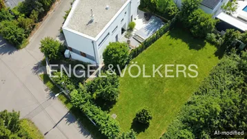 Luftaufnahme eines modernen Hauses mit Flachdach, großem Garten und gepflasterter Terrasse mit Poolabdeckung.