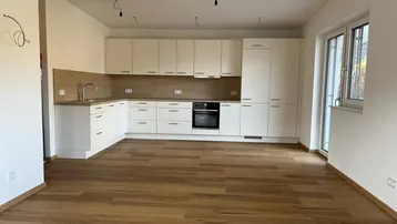 Neue, helle Küche mit weißen Schränken, Holzakzenten und modernem Holzboden.